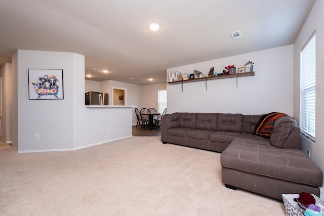 living room with light carpet, plenty of natural light, and a textured ceiling