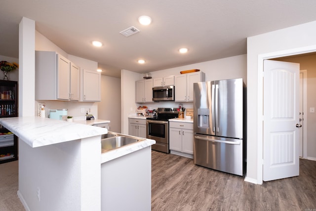 kitchen with a kitchen bar, kitchen peninsula, stainless steel appliances, and hardwood / wood-style flooring