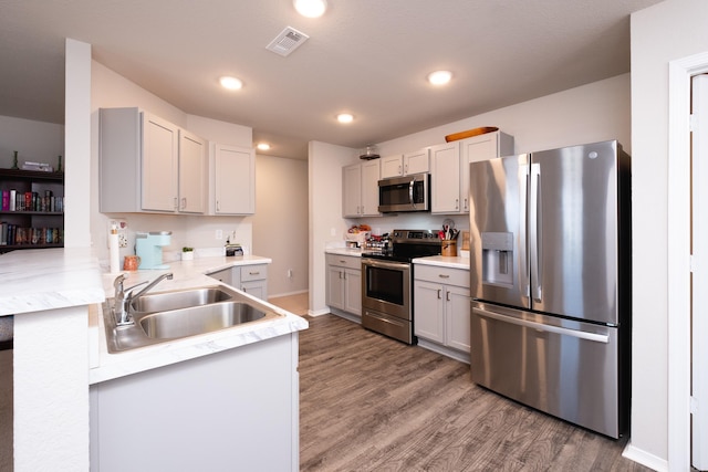 kitchen with hardwood / wood-style floors, sink, kitchen peninsula, and stainless steel appliances