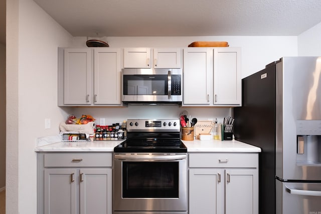 kitchen with white cabinets, a textured ceiling, and stainless steel appliances