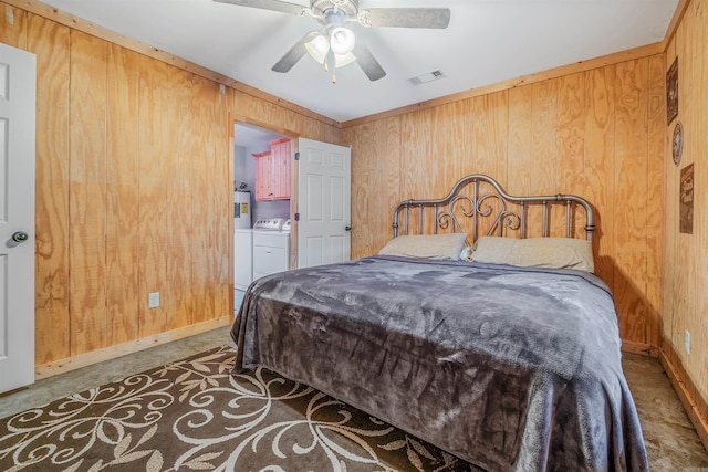 bedroom featuring washing machine and clothes dryer, ceiling fan, and wood walls