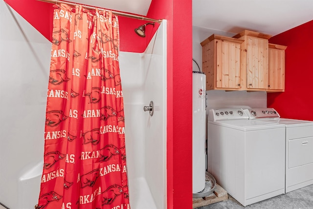 clothes washing area featuring washing machine and dryer, water heater, and cabinets