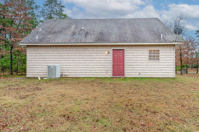 back of house with central air condition unit and a lawn