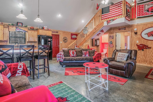 living room with wooden walls, sink, and lofted ceiling