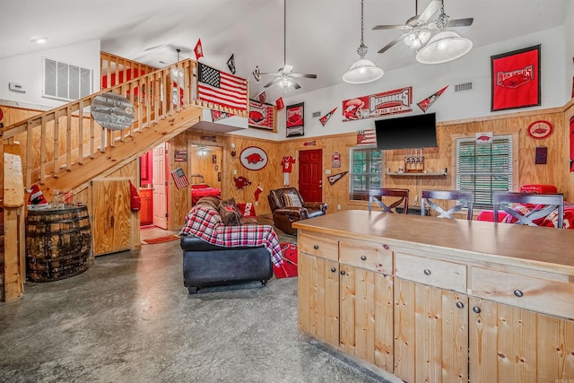 kitchen with wood walls, light brown cabinets, a towering ceiling, and concrete floors