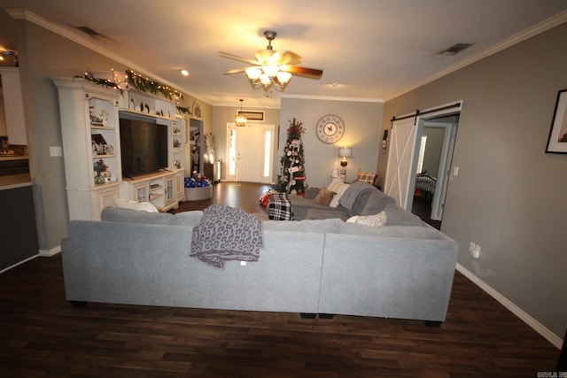 living room featuring a barn door, ceiling fan, dark wood-type flooring, and ornamental molding