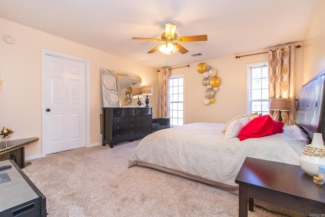 carpeted bedroom featuring multiple windows and ceiling fan