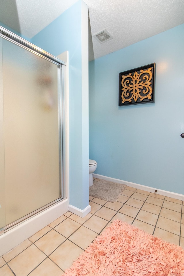 bathroom featuring toilet, tile patterned flooring, a textured ceiling, and walk in shower