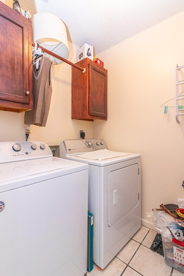 laundry room featuring light tile patterned flooring, cabinets, a textured ceiling, and independent washer and dryer