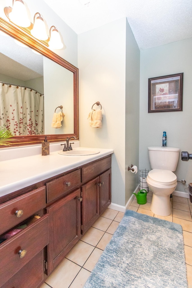 bathroom with tile patterned floors, vanity, toilet, and a textured ceiling