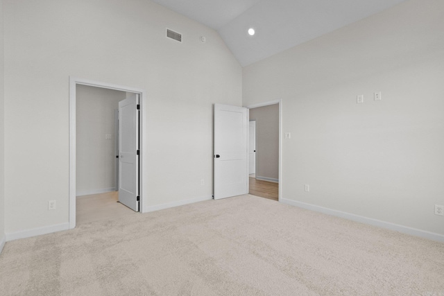 unfurnished bedroom featuring light colored carpet and high vaulted ceiling