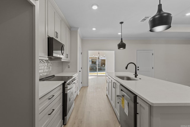 kitchen featuring appliances with stainless steel finishes, a kitchen island with sink, sink, white cabinets, and hanging light fixtures