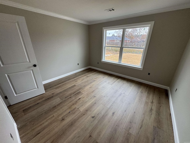 spare room with hardwood / wood-style floors and crown molding