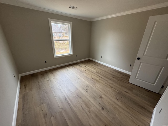 spare room featuring light hardwood / wood-style flooring and crown molding