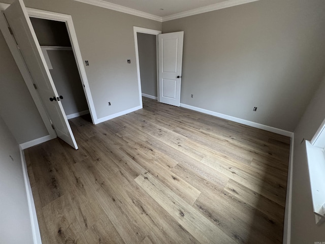 unfurnished bedroom with crown molding, a closet, and light wood-type flooring