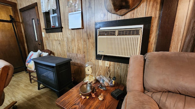 living room featuring wood-type flooring, an AC wall unit, a wood stove, and wooden walls