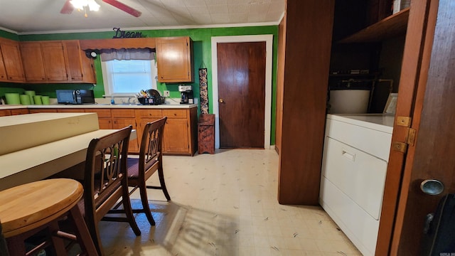 kitchen with washer / clothes dryer, crown molding, and ceiling fan