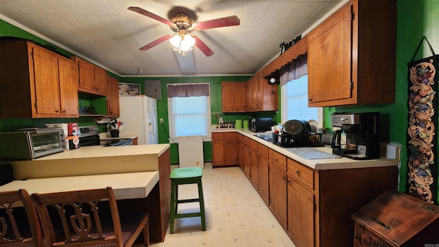 kitchen with stainless steel range with electric stovetop, ceiling fan, crown molding, white refrigerator, and a breakfast bar area