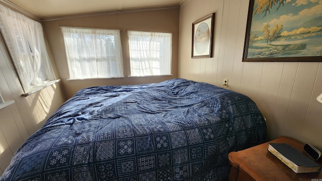 bedroom featuring wooden walls and crown molding