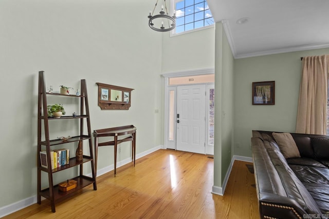 entrance foyer with a notable chandelier, ornamental molding, and light hardwood / wood-style flooring