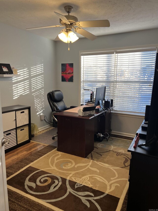 home office with dark colored carpet, ceiling fan, and a textured ceiling