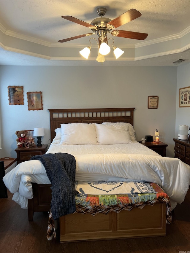 bedroom featuring ceiling fan, dark wood-type flooring, crown molding, a textured ceiling, and a tray ceiling