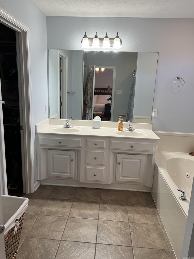 bathroom featuring a tub, tile patterned flooring, vanity, and a textured ceiling