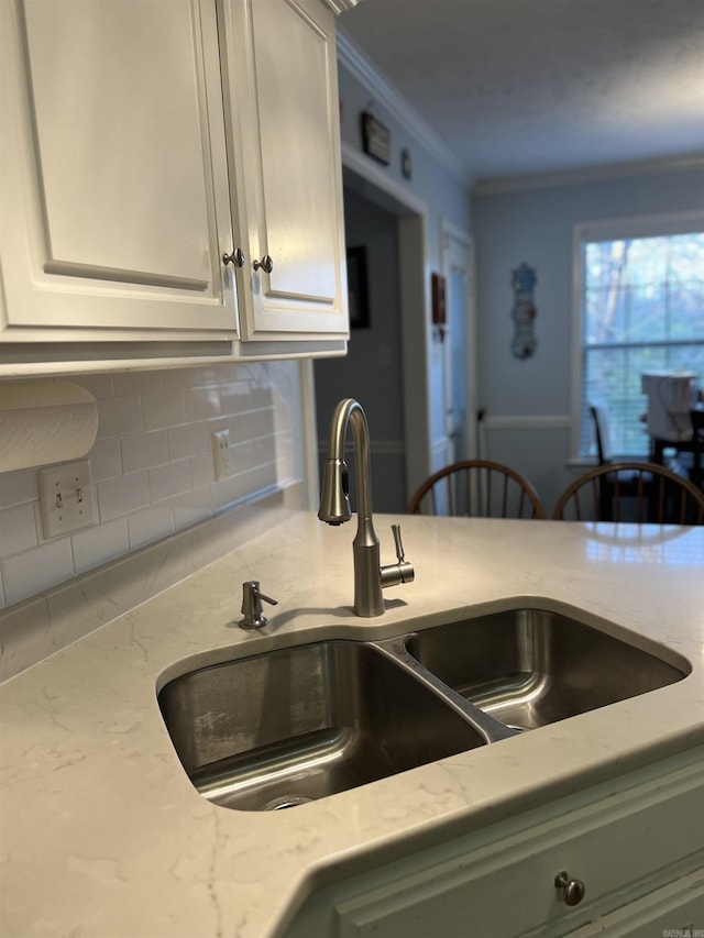 kitchen featuring crown molding, light stone countertops, sink, and tasteful backsplash