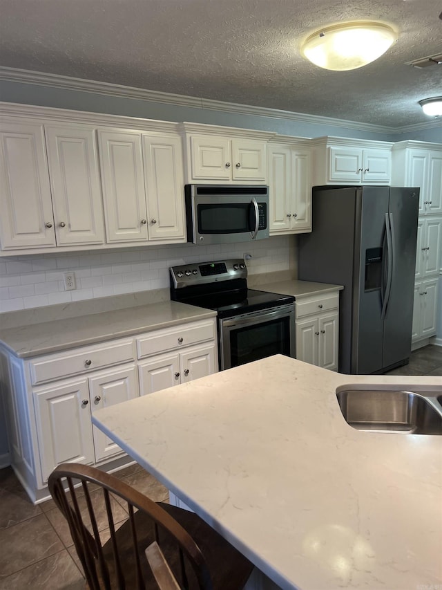 kitchen with white cabinets, backsplash, and appliances with stainless steel finishes