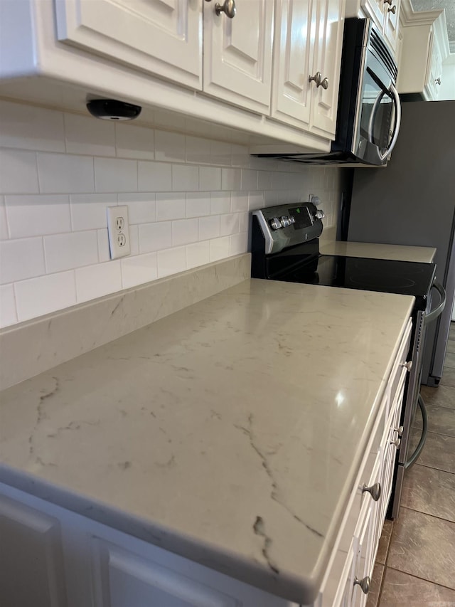 kitchen featuring backsplash, black / electric stove, light stone countertops, and white cabinets