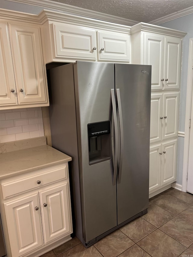 kitchen featuring stainless steel refrigerator with ice dispenser, backsplash, crown molding, a textured ceiling, and dark tile patterned flooring