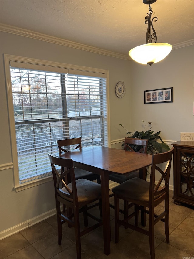 dining area with a healthy amount of sunlight, dark tile patterned floors, and crown molding