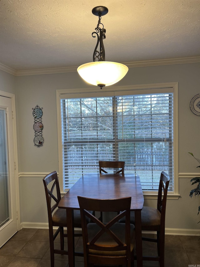 dining area with a textured ceiling, dark tile patterned flooring, and ornamental molding