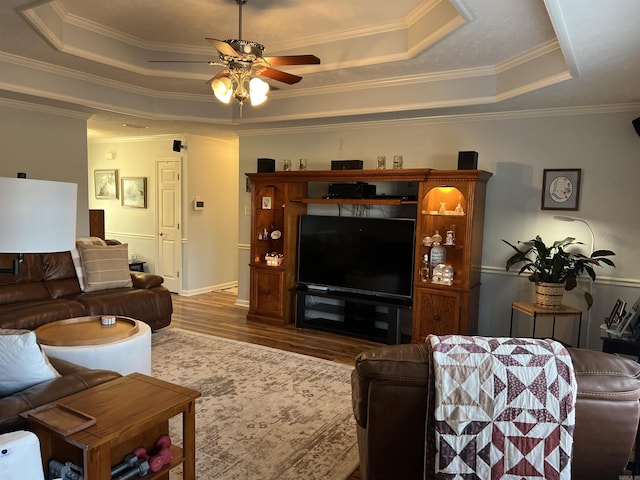 living room with dark hardwood / wood-style flooring, a raised ceiling, and crown molding