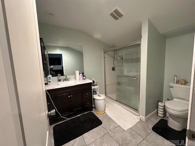 bathroom featuring vanity, vaulted ceiling, tile patterned flooring, toilet, and a shower with shower door