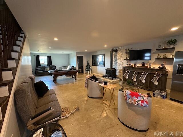 living room featuring concrete floors, a wood stove, and pool table