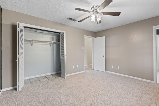 unfurnished bedroom with light carpet, a textured ceiling, a closet, and ceiling fan