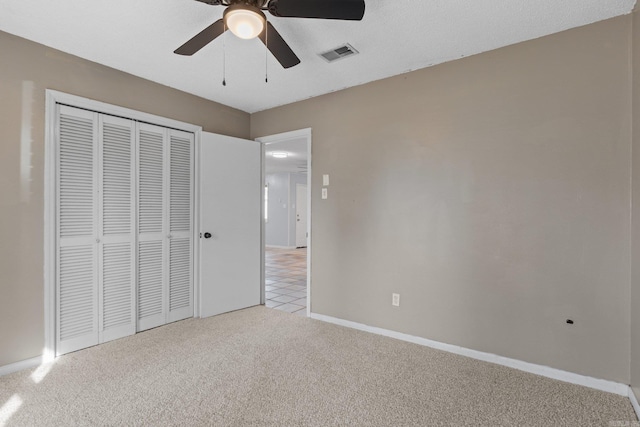 unfurnished bedroom featuring light carpet, a closet, and ceiling fan