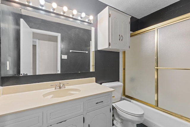 full bathroom featuring toilet, combined bath / shower with glass door, a textured ceiling, and vanity