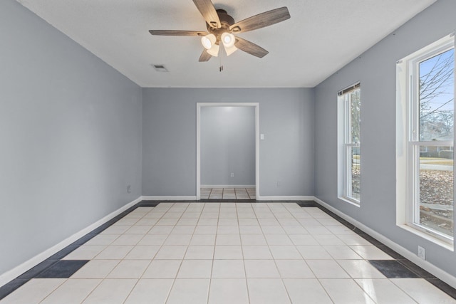 empty room featuring light tile patterned floors, a textured ceiling, and ceiling fan