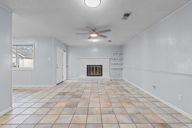 unfurnished living room with ceiling fan, a fireplace, light tile patterned floors, and a textured ceiling