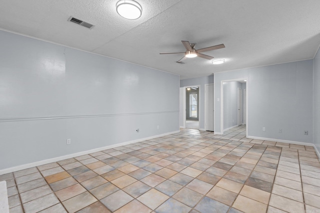 spare room featuring ceiling fan, light tile patterned flooring, and a textured ceiling