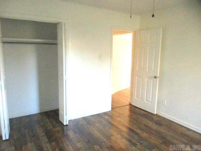 unfurnished bedroom with dark hardwood / wood-style flooring and a closet