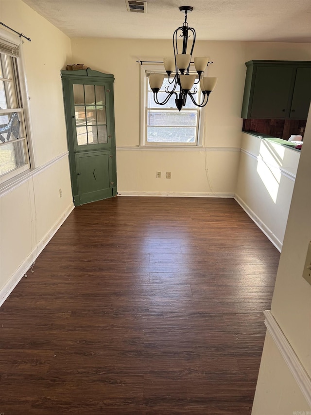 unfurnished dining area featuring a notable chandelier and dark wood-type flooring