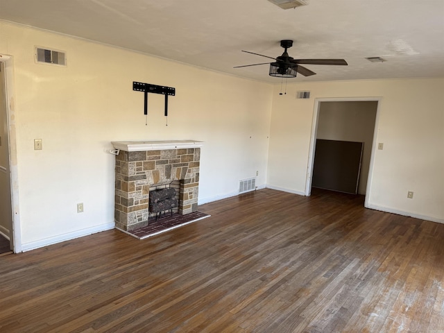 unfurnished living room featuring dark hardwood / wood-style floors, a stone fireplace, and ceiling fan