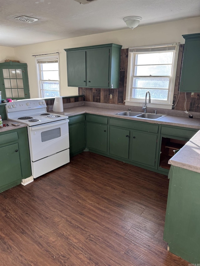 kitchen with a healthy amount of sunlight, electric stove, sink, and green cabinetry