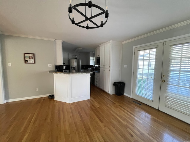 kitchen with french doors, white cabinets, appliances with stainless steel finishes, a notable chandelier, and wood-type flooring