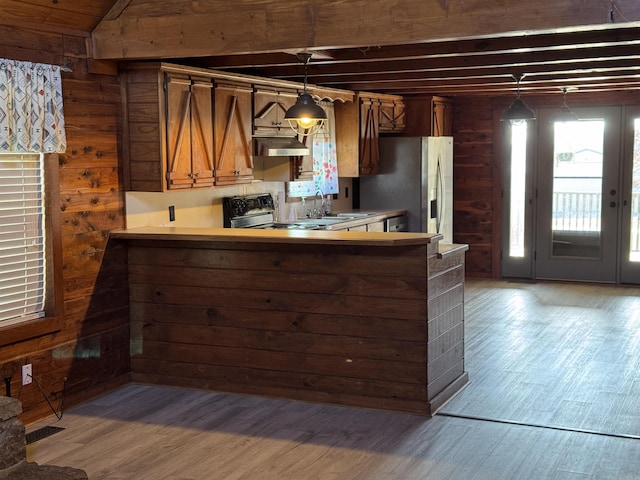 kitchen with kitchen peninsula, wood walls, decorative light fixtures, hardwood / wood-style flooring, and appliances with stainless steel finishes