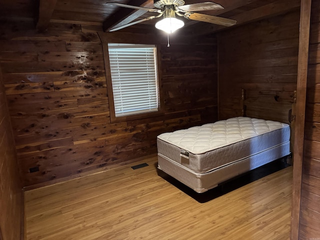 bedroom with beam ceiling, ceiling fan, hardwood / wood-style floors, wooden walls, and wood ceiling