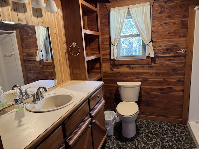 bathroom with vanity, toilet, and wooden walls